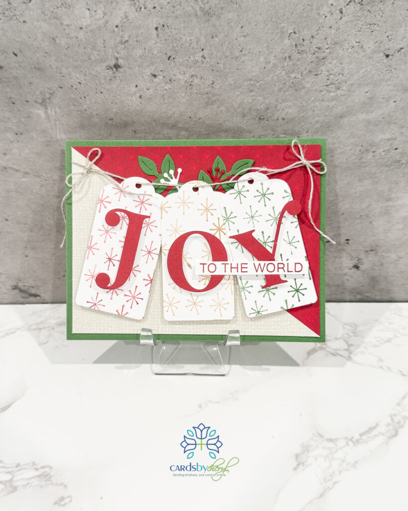 A red, white, and green Christmas card with the word "JOY" on the front